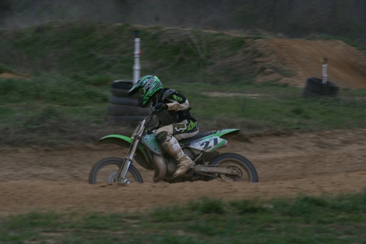 Kawasaki rider number 27 in a corner at dusk